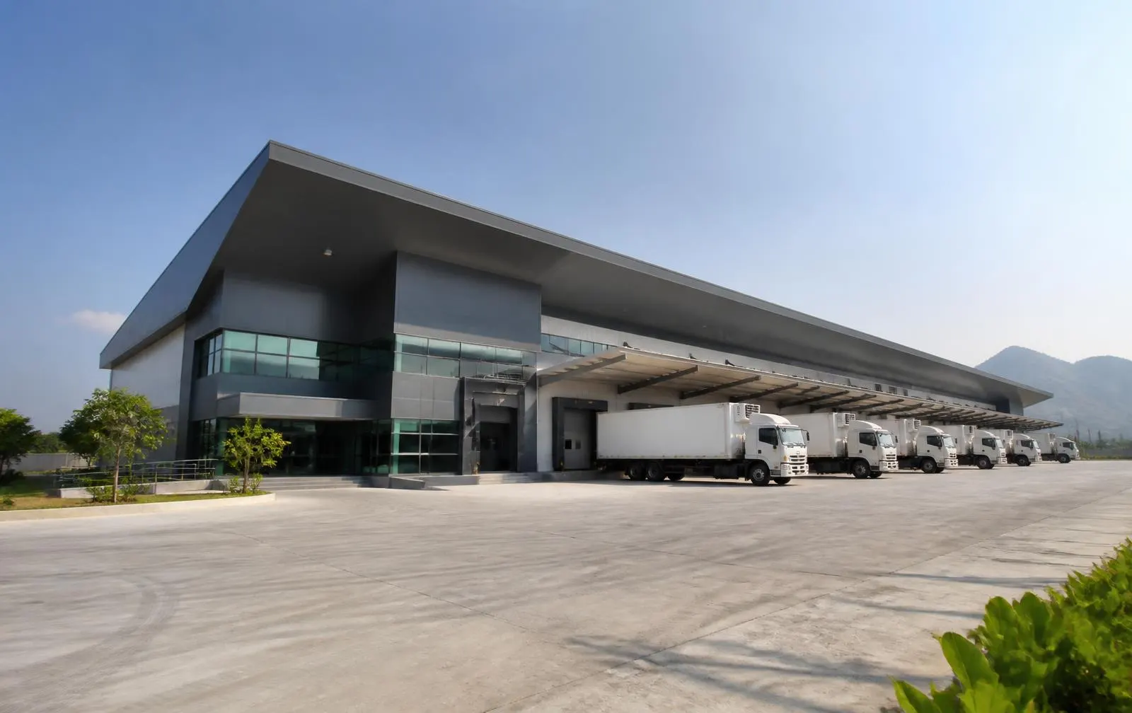 Exterior of a modern fruit pack house with loading bays and refrigerated trucks